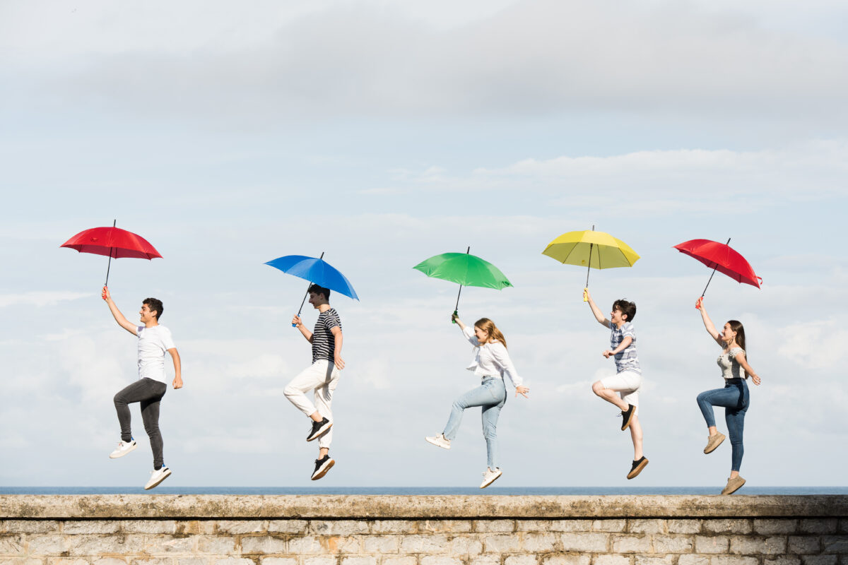 Jugendliche balancieren mit bunten Regenschirmen