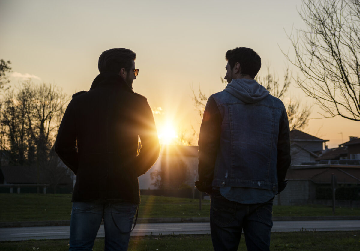Zwei junge Männer schauen in den Sonnenuntergang