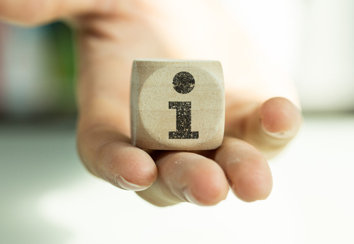 Hand hält großen Holzwürfel mit dem Buchstaben i