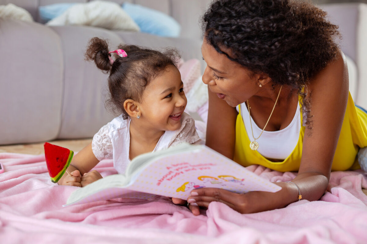 Mutter und Kind beim gemeinsamen Lesen am Boden