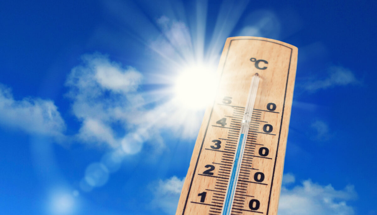 Thermometer wird in Richtung Himmel in die Sonne gehalten.