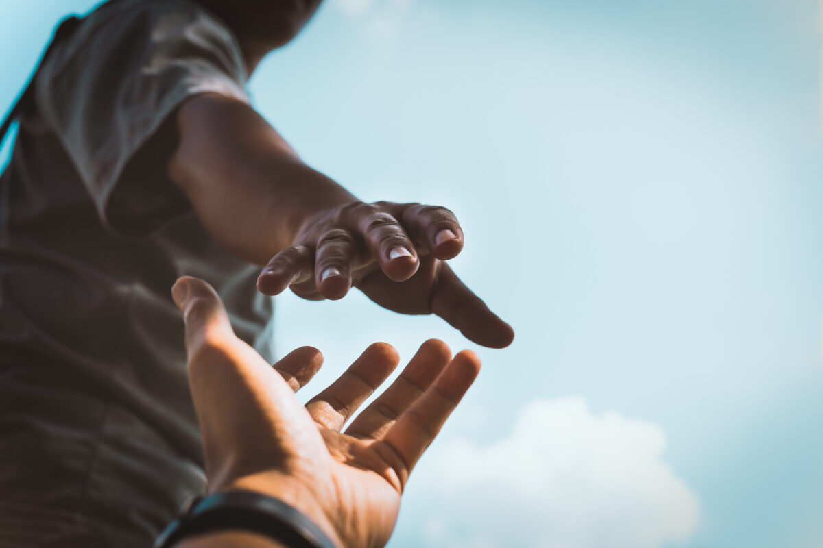 Person streckt ihre Hand in Richtung einer anderen Hand
