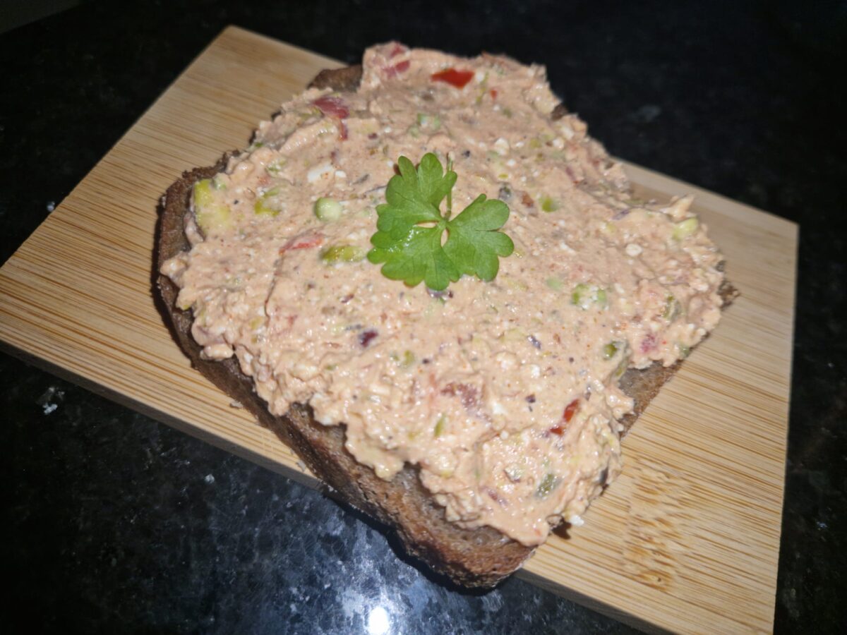 Eine Scheibe Brot mit Pistazien-Tomaten Aufstrich und einem Petersilienblatt