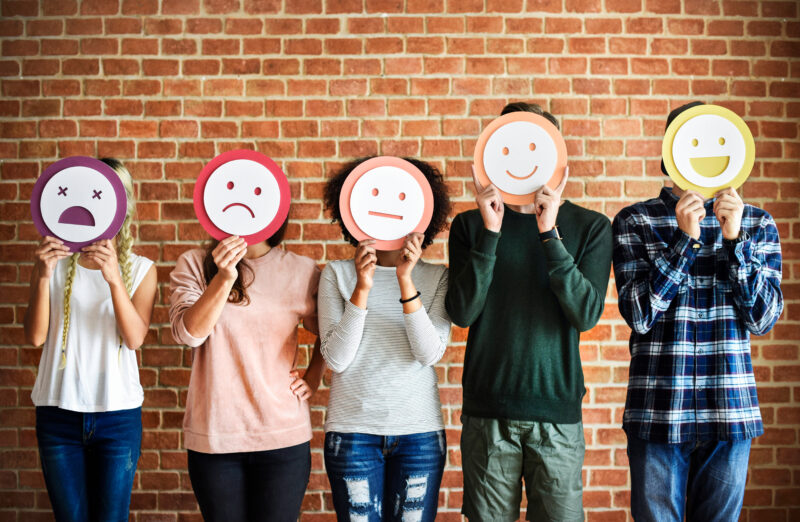 Junge Menschen mit Emojis vor dem Gesicht
