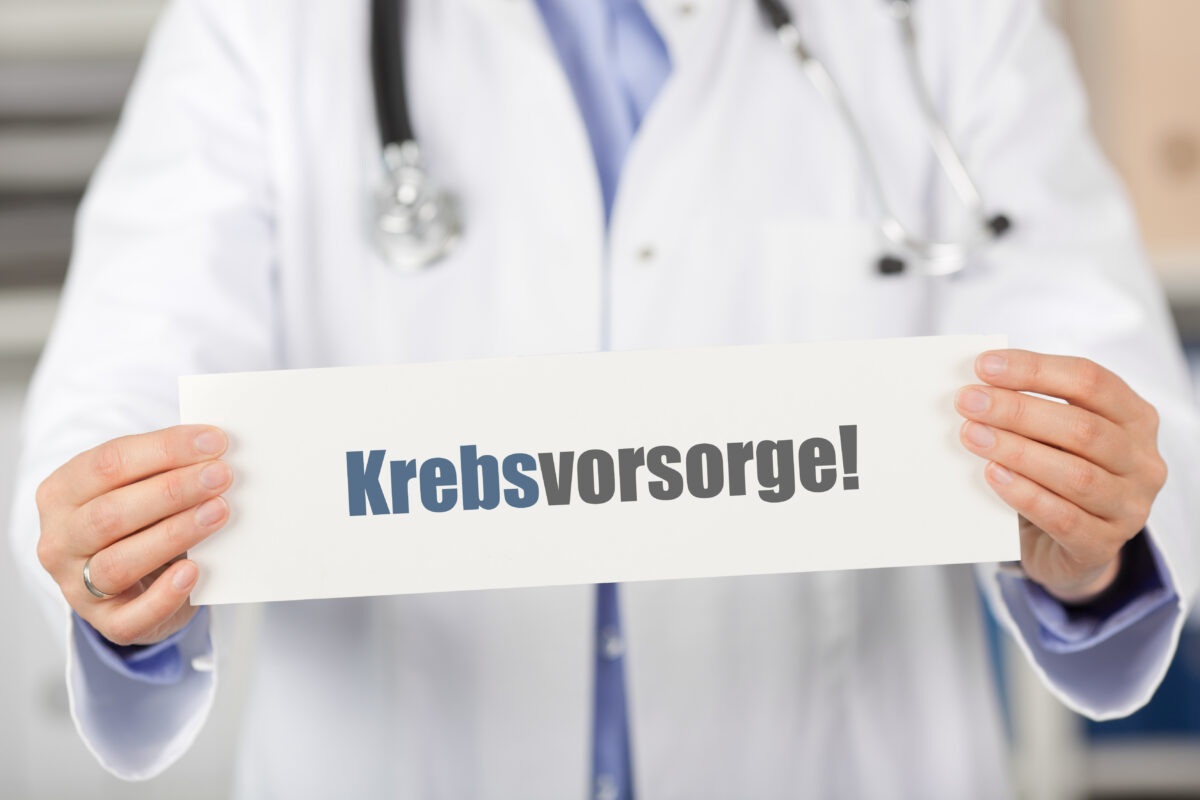 Arzt hält ein Schild mit dem Wort Krebsvorsorge